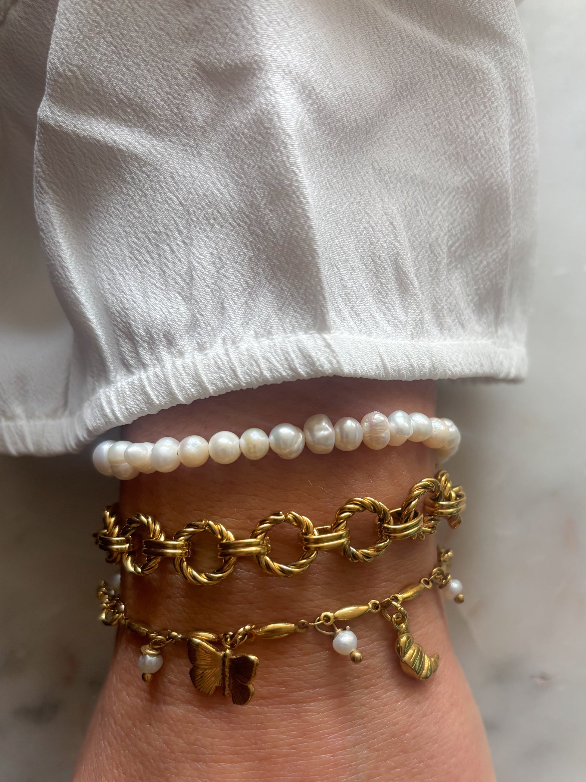 Pols met parel armband en rvs bedel en schakel armband